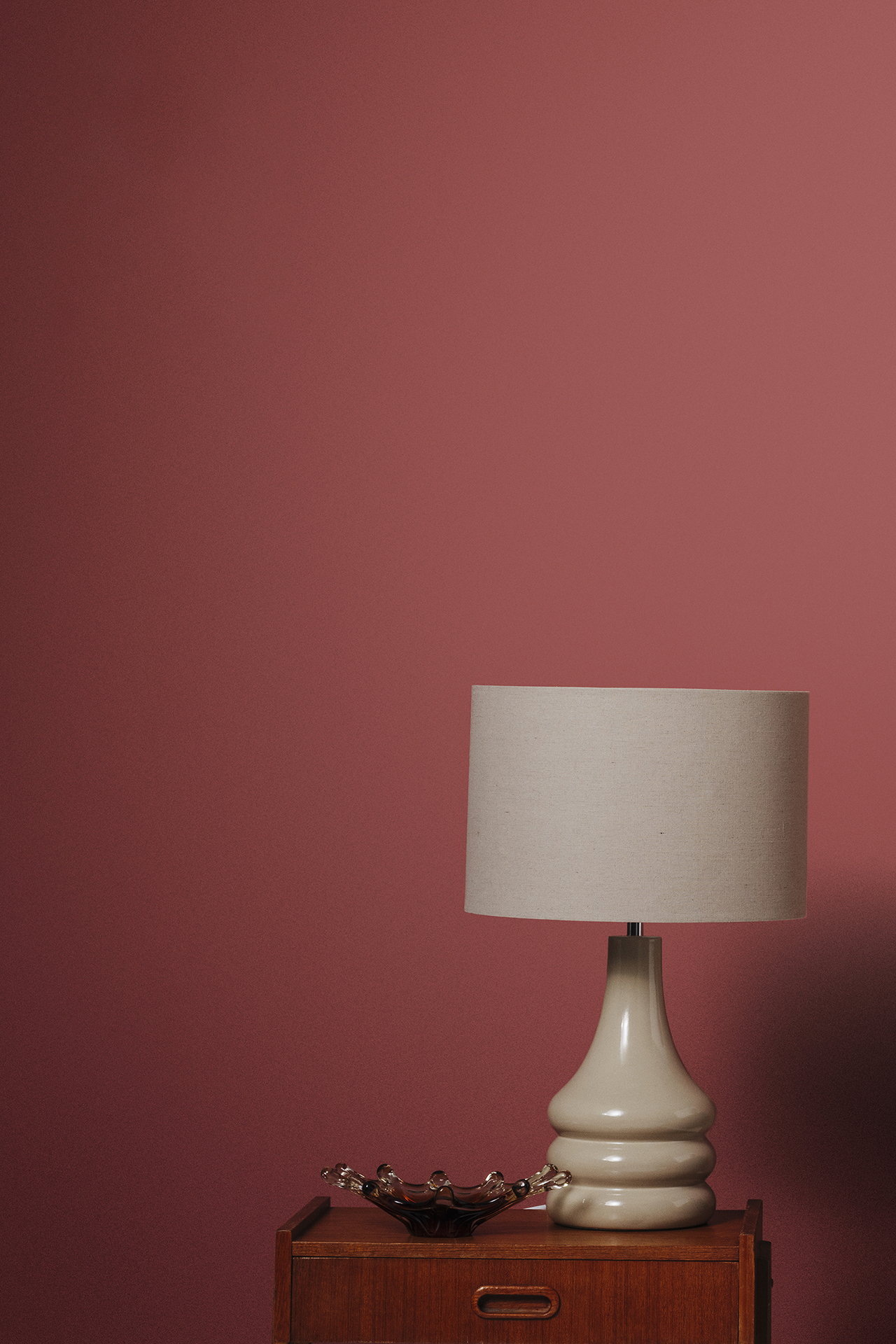 Lamp on side cabinet in front of red wall